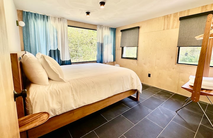 Минималистичните просторни спални разполагат с облицовани стени и елегантни подови настилки от шисти, които създават модерно и уютно място за отдих.