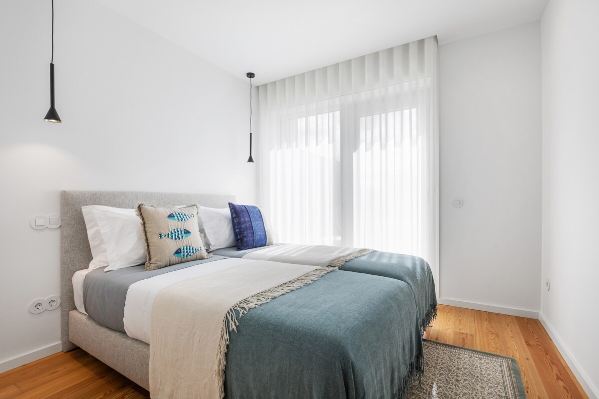 Dormitorio con dos camas individuales, armario empotrado y acceso a uno de los balcones.