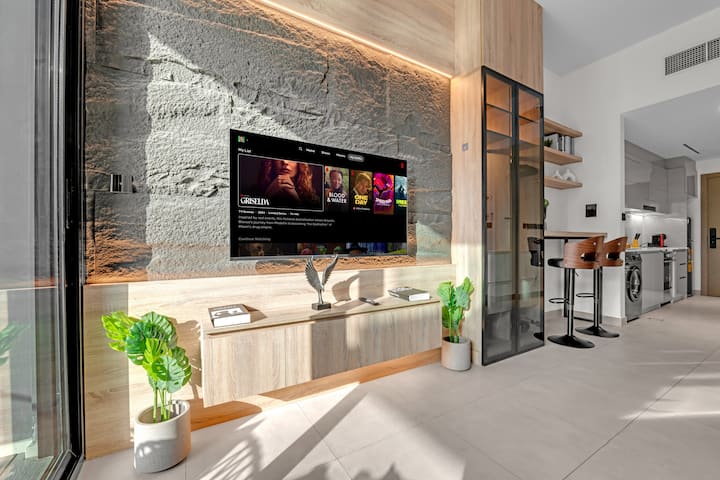 Sebule yenye nafasi kubwa na angavu yenye kitanda cha sofa cha starehe na televisheni mahiri ya inchi 50 iliyo na samani katika mtindo wa kisasa ili kutoa mazingira ya kifahari na ya kupumzika