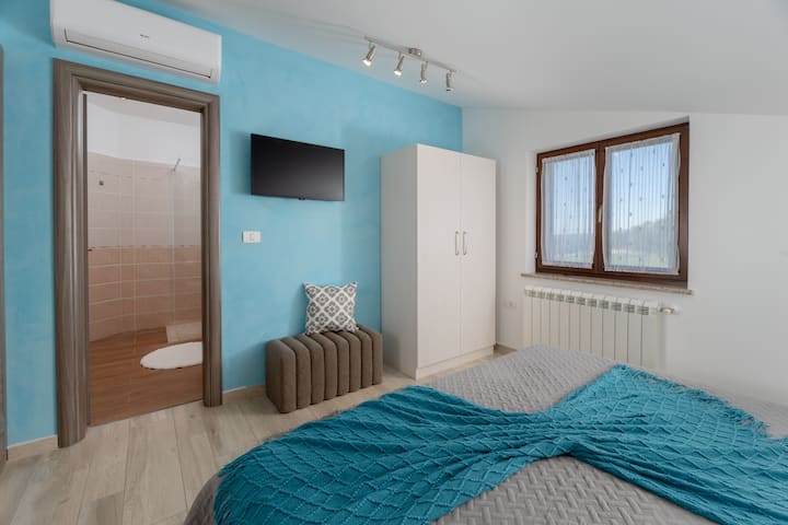 חדר שינה 3 מציע מיטה נוחה, טלוויזיה ואווירה מודרנית עם גישה ישירה לחדר הרחצה. הנכס המואר והפרקטי אידיאלי למנוחה אחרי יום באיסטריה.”