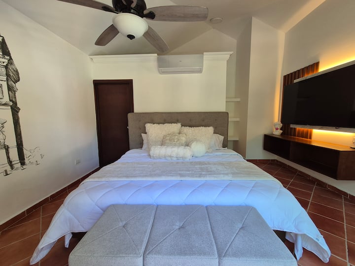 Exclusivo cuarto independiente junto a la casa principal, con balcón, cochera y baño privado. Su diseño, inspirado en la elegancia de la antigua Roma, crea un ambiente íntimo y sofisticado ideal para el descanso.