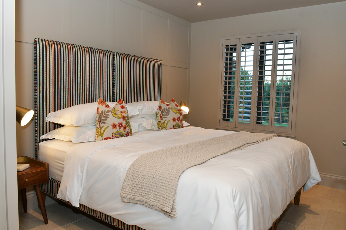 Основна спалня със суперголямо легло (може да бъде разделена на 2 единични при поискване). Самостоятелно помещение с голям душ. Подово отопление с изглед към затворената частна градина. 