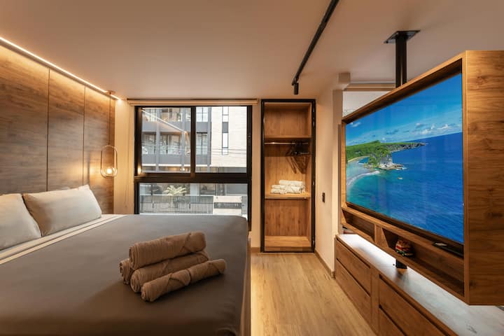 Потонете во подвижниот брачен кревет додека природната светлина се истура низ стаклениот ѕид. Дизајнерскиот плакар одржува сѐ елегантно на место, додека телевизорот од 65 инчи ги трансформира ноќите во приватен кино-луксуз и совршено комбинирана удобност.