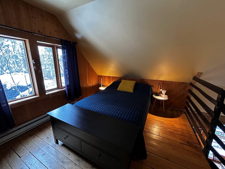 საძინებელს ღია გეგმარებით, რომელიც ანტრესოლზეა, აქვს დიდი ფანჯარა და ყველა საჭირო კომფორტი სასიამოვნო სტუმრობისთვის.