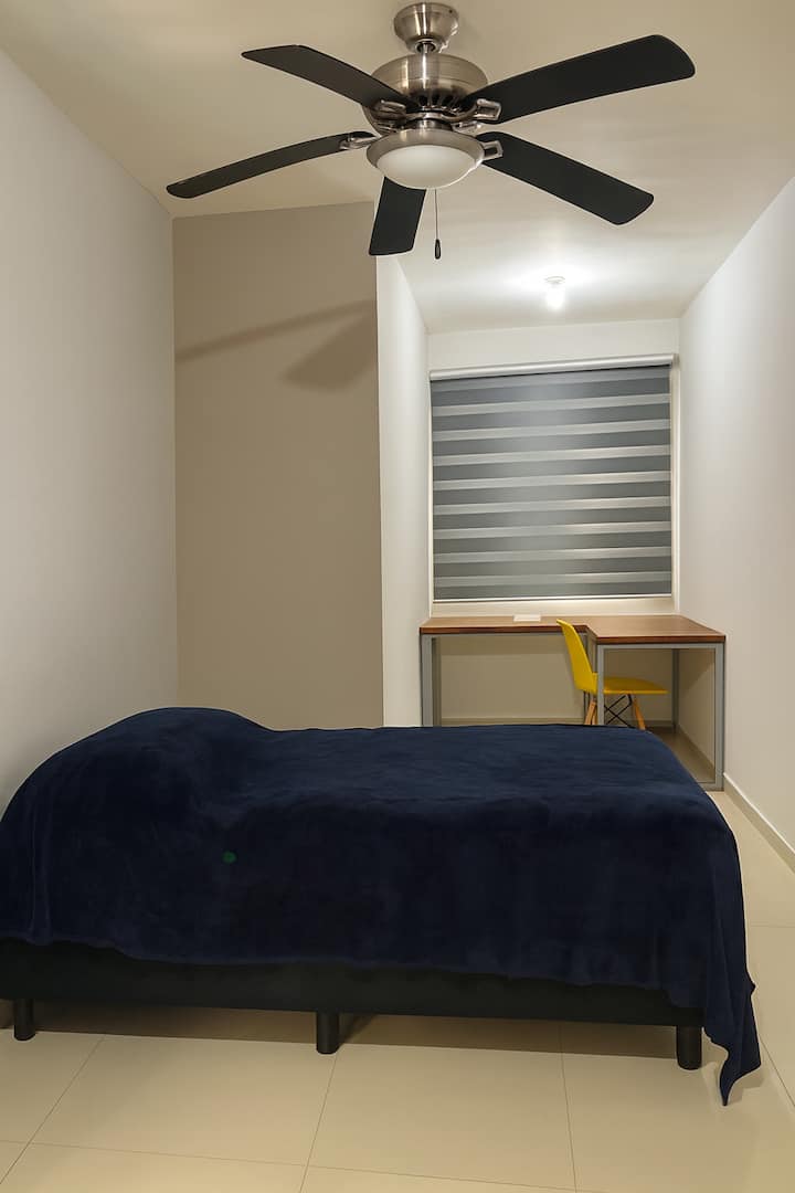 Izba s jednolôžkom, pracovným stolom a plným šatníkom.