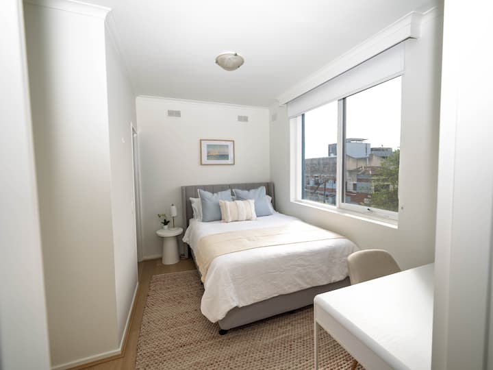 Уютна спалня с двойно легло, меко спално бельо, много естествена светлина и малко работно пространство. Перфектен за спокоен престой.