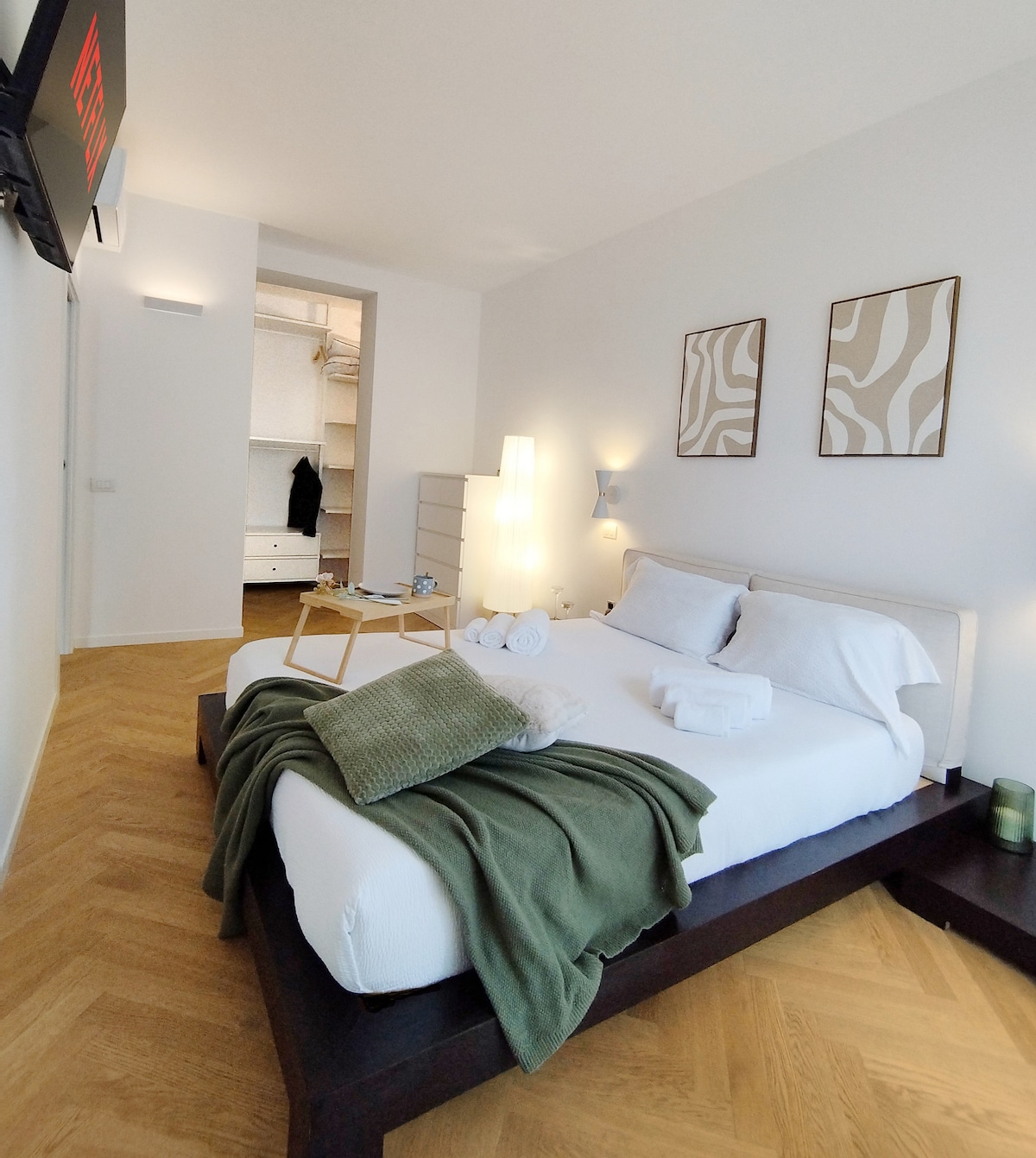 Elegante dormitorio principal con vestidor contiguo, televisor inteligente de 43 pulgadas, lámparas de lectura, mantas adicionales y almohadas de espuma viscoelástica, diseñado para garantizar el máximo descanso, relajación y elegancia en un ambiente cálido y refinado.