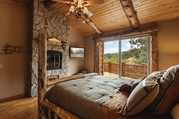 Suite principale spacieuse avec foyer en pierre et balcon privé avec vue sur la montagne.