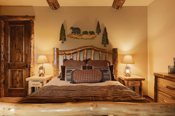 Lit queen size avec art mural sur le thème de la forêt et meubles en bois naturel.