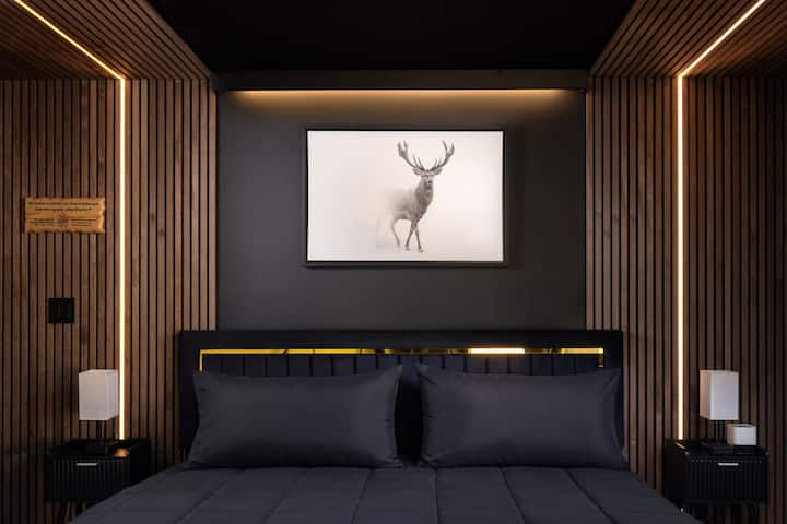 A dramatic bedroom with a plush headboard, layered lighting, and striking wildlife art, offering a private and comfortable space to rest after a full day outdoors.