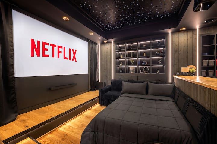 Sink into the lounging bed for a cozy movie night on the big screen, wrapped in soft lighting and a starry ceiling for the ultimate cinema experience at home.