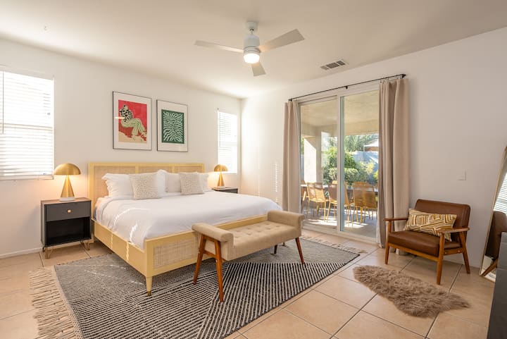 Dormitorio n.º 1: (principal) cama tamaño king con baño privado, mesitas de noche, lámparas de mesa, banco final, silla decorativa, salida al patio trasero 