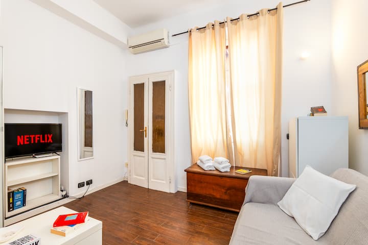 Dnevni boravak je svijetao i ugodan, opremljen udobnim kaučem i pametnim televizorom s Netflixom za opuštanje nakon dana u gradu. Velike zavjese filtriraju prirodno svjetlo, stvarajući topao i ugodan ambijent.