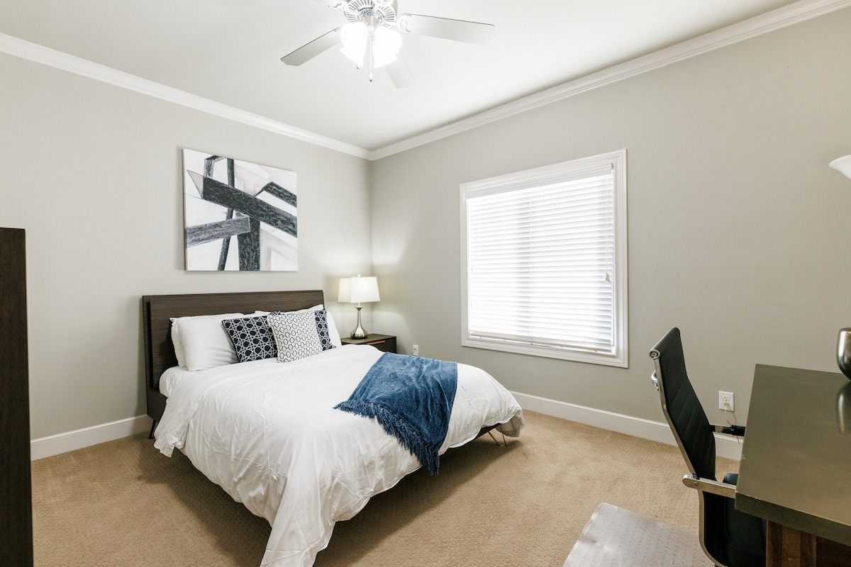 Светла спалня на горния етаж с двойно легло, бюро и стол и много естествена светлина, идеална за почивка или работа по време на престоя ви.