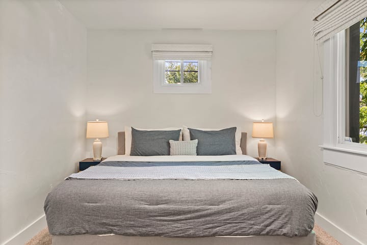 ห้องนอนชั้นบนกว้างขวางพร้อมเตียงขนาดคิงไซส์ โต๊ะข้างเตียงมีโคมไฟพร้อมเต้ารับในตัวและพอร์ต USB-C เพื่อให้ชาร์จได้ง่าย