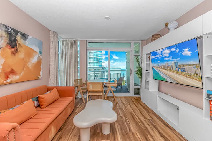 Ambiente de playa moderno: elegante sala de estar con TV inteligente, comedor y acceso al balcón para el refugio costero perfecto 