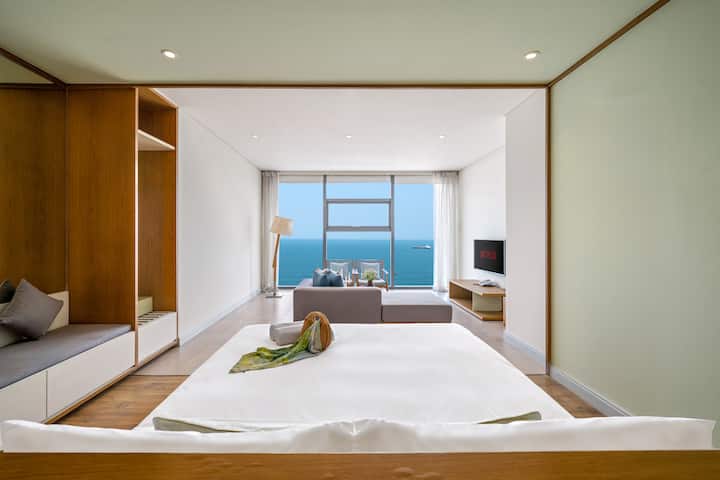 Una cama tamaño king con sábanas premium promete noches de descanso y despertares suaves con vistas al mar. El servicio de limpieza diario garantiza sábanas frescas, toallas limpias y un refugio impecable, convirtiendo esta habitación en un santuario de calma, estilo y renovación.