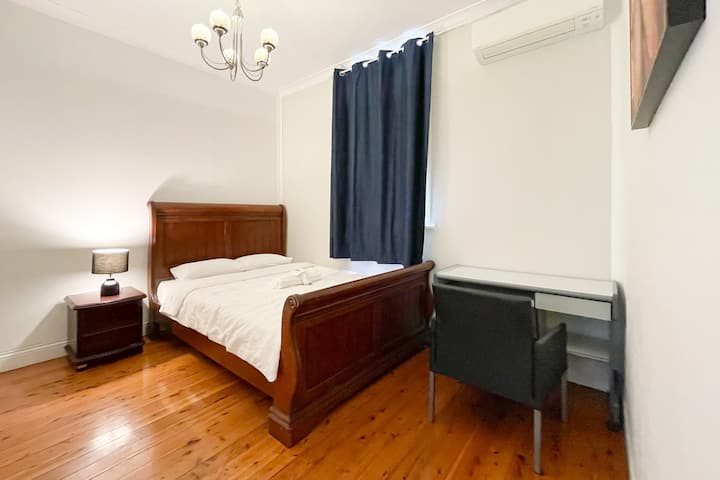 ผ่อนคลายในห้องนอนที่อบอุ่นพร้อมเตียงไม้เนื้อแข็ง แสงไฟสว่างนุ่มนวล และม่านสำหรับการนอนหลับพักผ่อนยามค่ำคืน