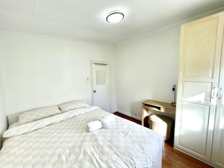 ห้องนอนที่สว่างและอบอุ่นพร้อมเตียงหรูหรา เครื่องปรับอากาศ และแสงธรรมชาติที่นุ่มนวล