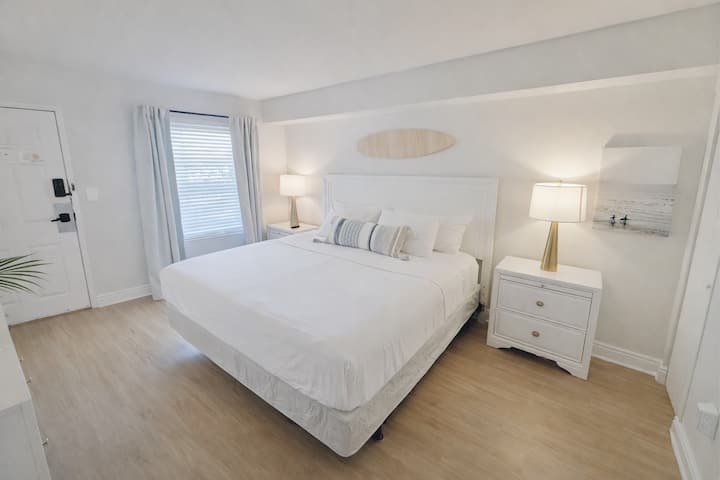 “Suite King luminosa con diseño costero y ropa de cama de lujo”
Amplio dormitorio tamaño king con ropa de cama blanca y fresca, cortinas opacas e iluminación ambiental suave para noches de descanso después de un día en la playa.