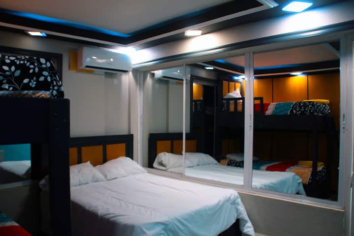 Dhomë e projektuar për grupe ose familje, e pajisur me një krevat dopio dhe një krevat dopio, e përkryer për të akomoduar disa vizitorë pa humbur rehatinë. Ka ajër të kondicionuar, një pasqyrë të madhe me dyer rrëshqitëse dhe ndriçim të mirë.