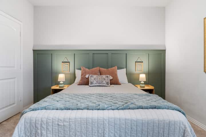 พักผ่อนในห้องสีเขียวที่อบอุ่นของเรา พร้อมโต๊ะข้างเตียงที่มีปลั๊กไฟสำหรับชาร์จอุปกรณ์ของคุณอย่างสะดวกสบาย