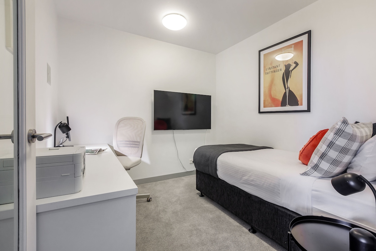 استمتع بالاسترخاء في غرفة النوم الثانية التي تحتوي على سرير فردي كبير وتلفزيون خاص وإضاءة محيطة ومساحة عمل مخصصة.