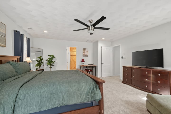 Útulná spálňa s manželskou posteľou, stropným ventilátorom a komodou pre väčšie pohodlie.