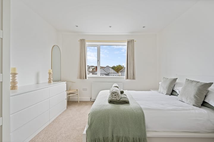 Peaceful double bedroom with soft tones, large window views, and plush bedding for restful nights. Ideal for couples or friends, featuring modern décor, a spacious dresser, and calming natural light for a relaxed Poole getaway.

