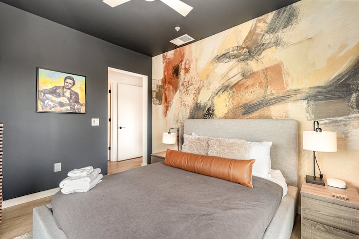 Luxe primary bedroom with balcony access, city views, king bed, smart TV, and soft curtains—bright, private, and perfect for relaxing after a day out.