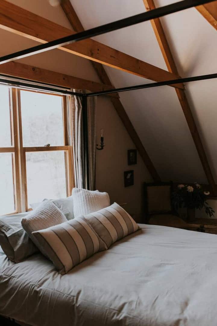 The primary bedroom features vintage decor and a canopy queen bed draped with luxurious netting.