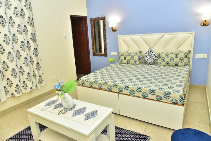 Светла спалня с голямо двойно легло, първокласен син интериор и прилежаща баня.