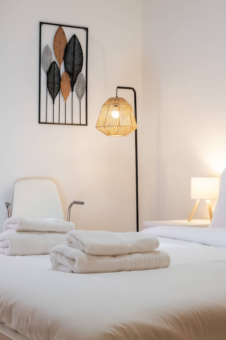 Acogedora y serena habitación con sábanas blancas y frescas, iluminación suave de una lámpara tejida y una elegante decoración con arte mural inspirado en la naturaleza. Un refugio tranquilo diseñado para la relajación y la comodidad. Perfecto para relajarse después de un día de exploración.