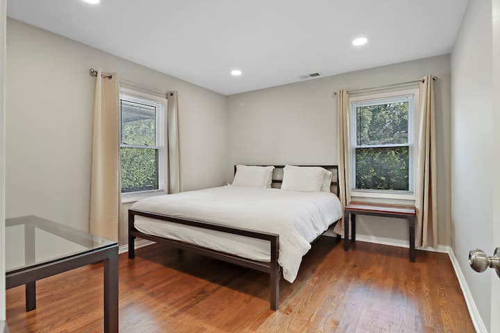 Táto spálňa ponúka manželskú posteľ s elegantným čiernym kovovým rámom, ktorý vytvára čistý a moderný vzhľad. Mäkká posteľná bielizeň a prirodzené svetlo robia priestor príjemným a pokojným.