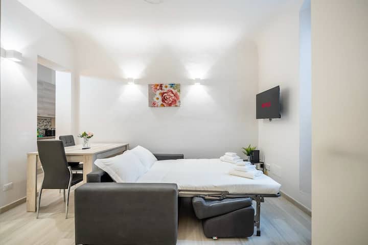 غرفة معيشة بها سرير أريكة وتلفزيون ذكي وطاولة طعام.