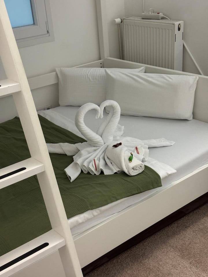 Gemütliches Schlafzimmer mit weißem Etagenbett und frischer Bettwäsche. Dekorative Handtuchfiguren auf dem Bett sorgen für einen einladenden Akzent und vermitteln ein gepflegtes Ambiente.
