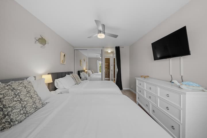 宁静的主楼卧室，配备两张豪华标准双人床、干净的床上用品和宁静的海岸色调。