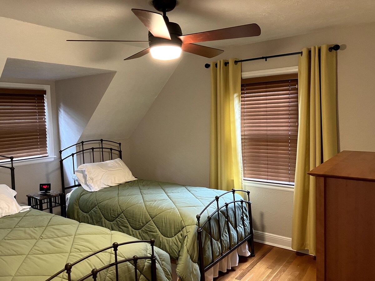 שתי מיטות יחיד נוחות עם שידה מימין. מעבר לשידת המגירות, יש ארון בגדים גדול.