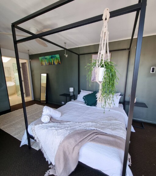 Chambre principale élégante avec un lit à baldaquin moderne, lumière naturelle et salle de bain privée, un havre de paix pour votre séjour à Scarborough.