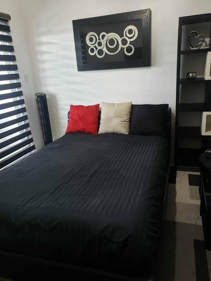 现代化卧室配有时尚的黑色床单、洁白的床单和柔软的枕头，并以红色和米色为主调，为您提供舒适时尚的放松空间。