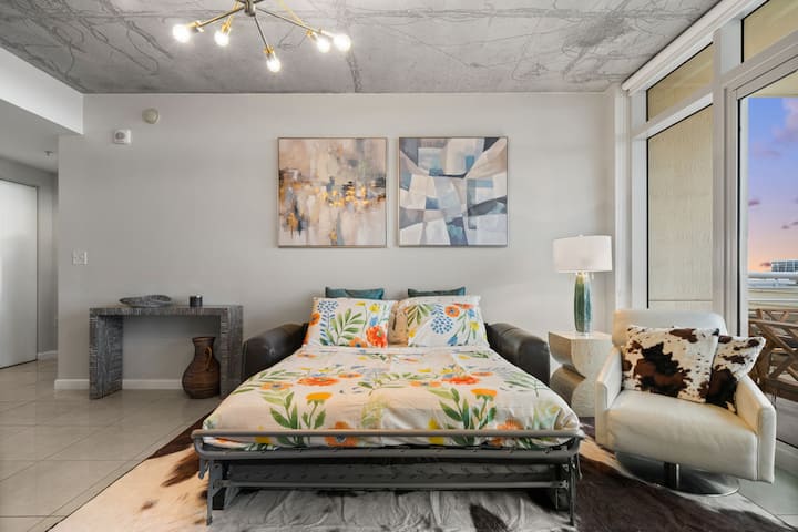 [Obývačka] Veľká kožená pohovka s dostatkom obytného priestoru. Vyskakujte plnohodnotnú posteľ, 65-palcovú SmartTV s prístupom na Netflix a balkón