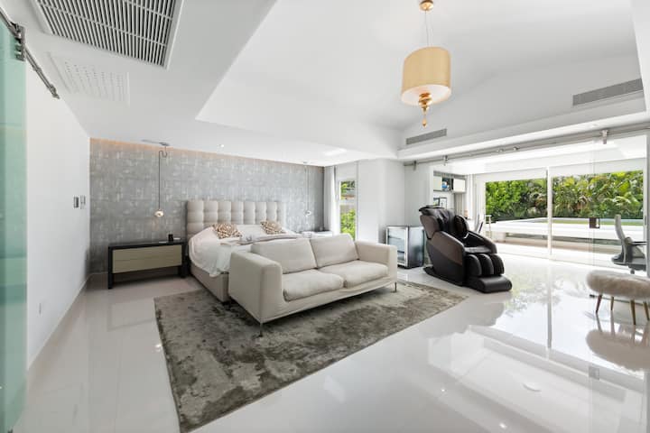 Amplia suite principal con cama tamaño king, zona de salón y acceso directo al jardín. Cuenta con un lujoso baño privado con ducha de cristal, bañera y dos lavabos, perfecto para relajarse con comodidad y privacidad.