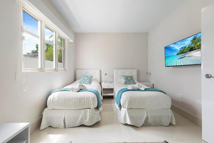 Luminoso dormitorio doble con dos camas individuales, decoración costera fresca y mucha luz natural. Ideal para amigos o niños, ofrece comodidad, aire acondicionado y un ambiente acogedor y espacioso