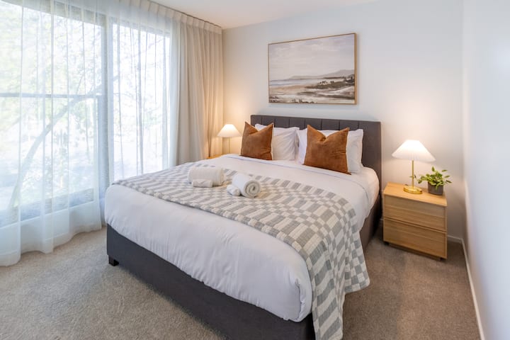 Zonnige en gastvrije slaapkamer met kingsize bed en zachte kussens.