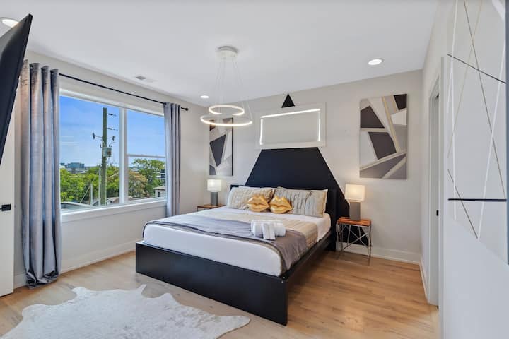 Modern king bedroom with smart TV, stylish décor, and plenty of natural light. Features cozy bedding, nightstands, and a relaxing layout—perfect for unwinding after a full day of exploring.