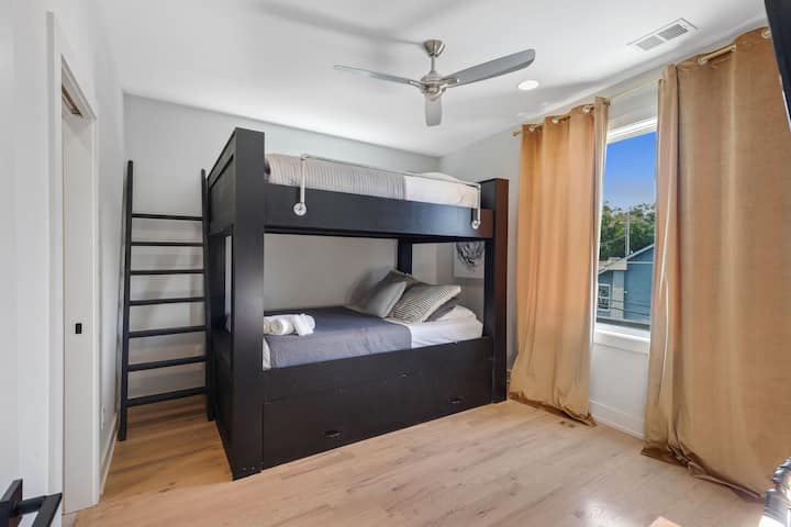 Spacious bunk room with twin-over-full beds, smart TV, ceiling fan, and natural light. Comfortable setup with modern finishes—perfect for kids, friends, or extra guests needing a flexible sleeping space.