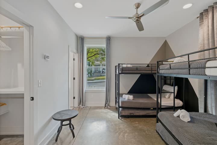 Large bunk room with multiple beds, ceiling fan, and natural light. Designed for groups with a comfortable layout, clean décor, and plenty of space for guests to sleep and recharge.