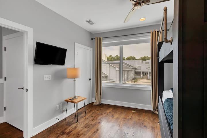 Bright bedroom with two queen beds, stylish décor, ceiling fan, and natural light. Comfortable bedding and a clean, modern design make this a great space for friends or family to relax and recharge.