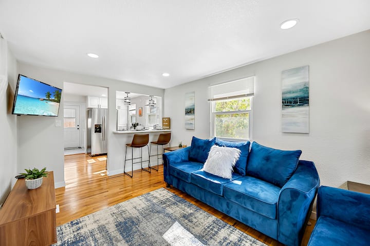 เข้าสู่สถานที่พักผ่อนที่อบอุ่นของคุณ! ห้องนั่งเล่นมีสมาร์ททีวี เกมที่หลากหลาย แสงไฟ และโซฟากำมะหยี่สีฟ้าที่สะดวกสบายสำหรับการพักผ่อนและพบปะสังสรรค์ การจัดวางแบบเปิดโล่งนำไปสู่ห้องครัวพร้อมบาร์อาหารเช้าพร้อมเก้าอี้บาร์ 4 ตัว