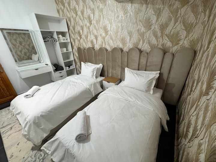 Ruime slaapkamer met twee bedden van één meter breed en twee meter lang, uitgerust met een kleedkamer, een tv met wifi en Netflix-abonnement en een werkruimte voor optimaal comfort tijdens je verblijf.
